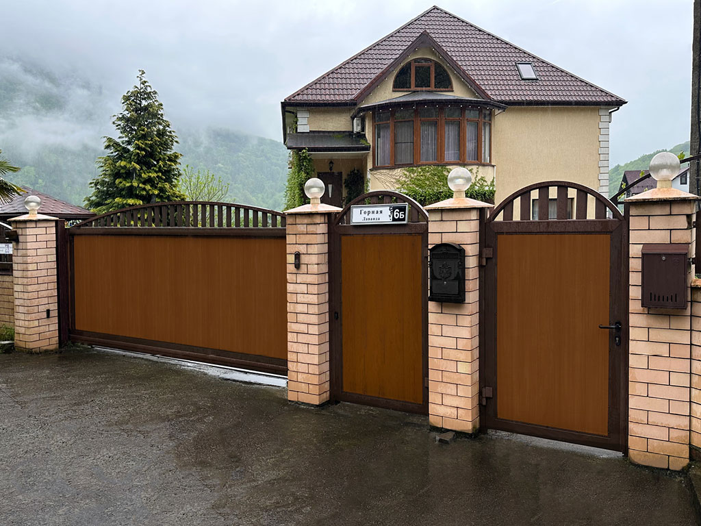 Сдвижные ворота с аркой и решеткой. Цвет полотна — «золотой дуб», цвет окантовки — RAL 8017 (коричнево-красный)