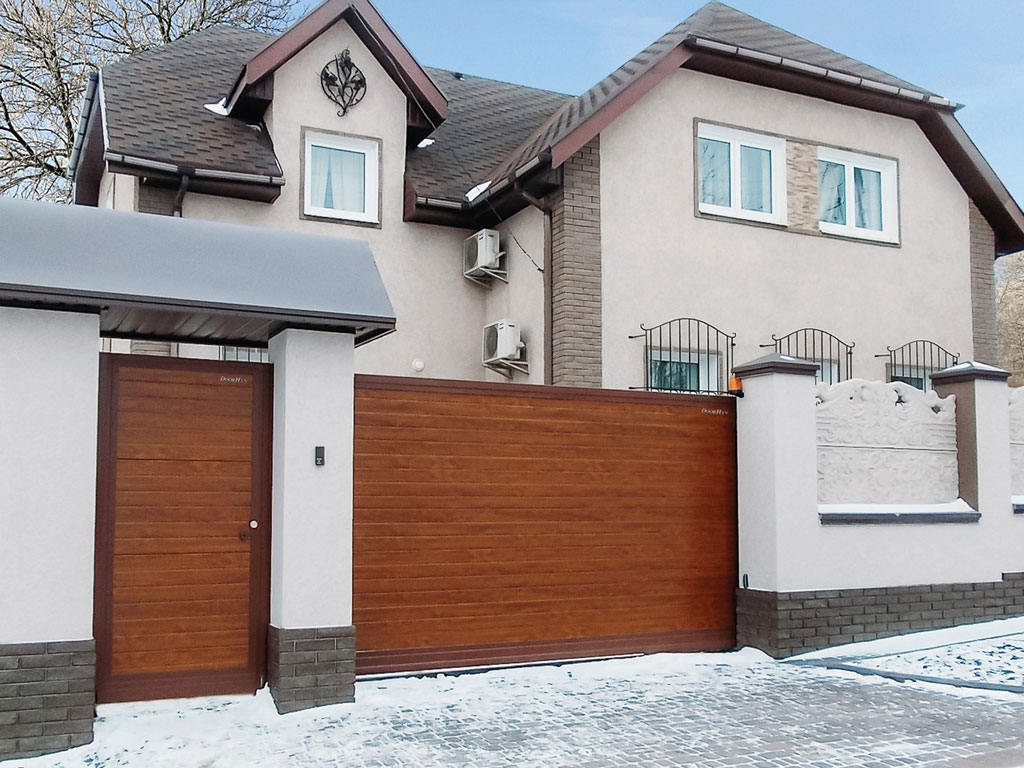 Сдвижные ворота с горизонтальным расположением панелей. Цвет полотна — «золотой дуб», цвет окантовки — RAL 8017 (коричнево-красный)